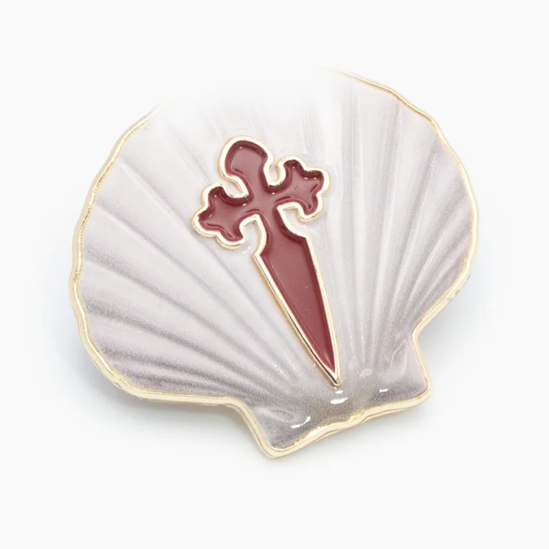 Pin 3D blanco esculpido con forma de concha de vieira y una cruz de Santiago roja en relieve