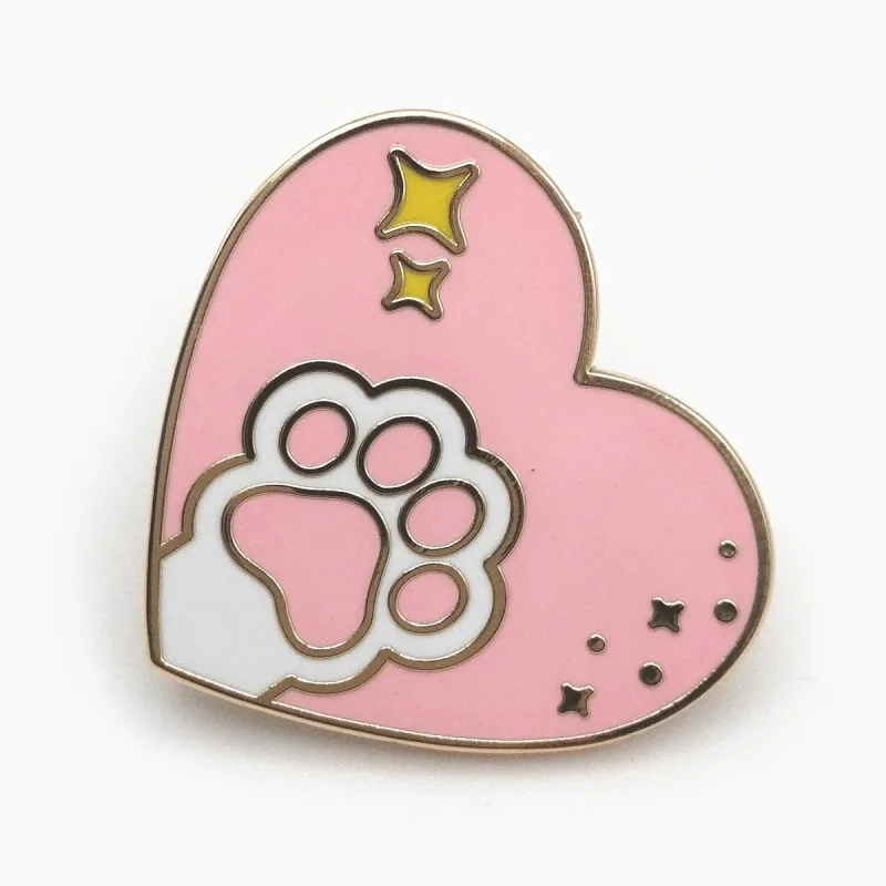 Pin de esmalte duro en forma de corazón rosa con una huella blanca y destellos dorados.