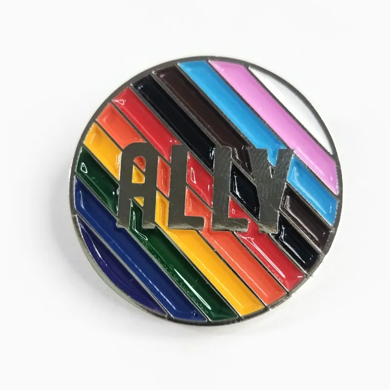 Pin redondo de esmalte con franjas diagonales de la bandera Progress Pride y el texto «ALLY» en relieve plateado.