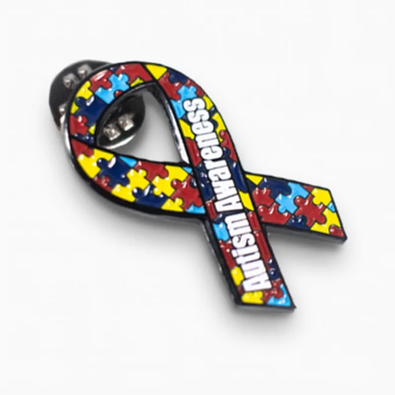 Pin de esmalte en forma de lazo con un patrón multicolor de piezas de rompecabezas y el texto «Autism Awareness».