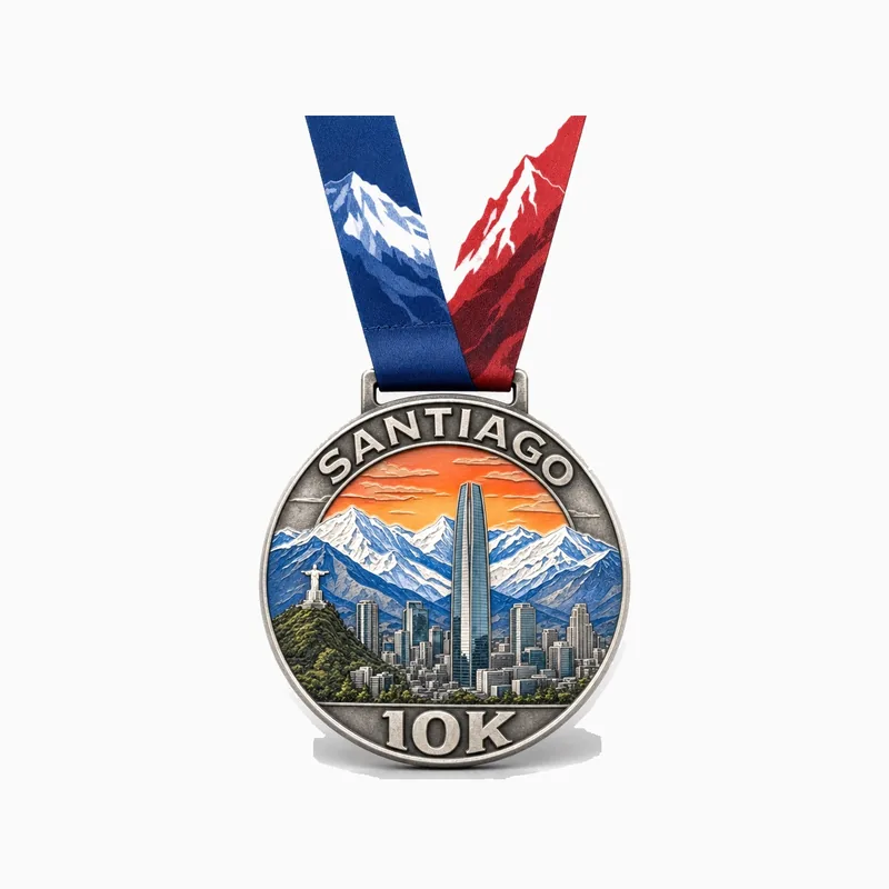 Medalla de plata antigua de la carrera SANTIAGO 10K con los Andes nevados, el perfil de la ciudad y esmalte de atardecer naranja, con cinta azul, blanca y roja con montañas