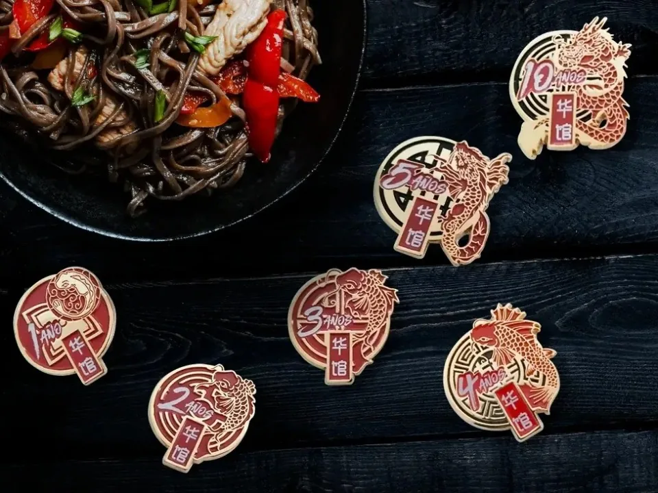 Pins dorados y rojos de esmalte por años de servicio que muestran un pez koi que poco a poco se transforma en dragón.