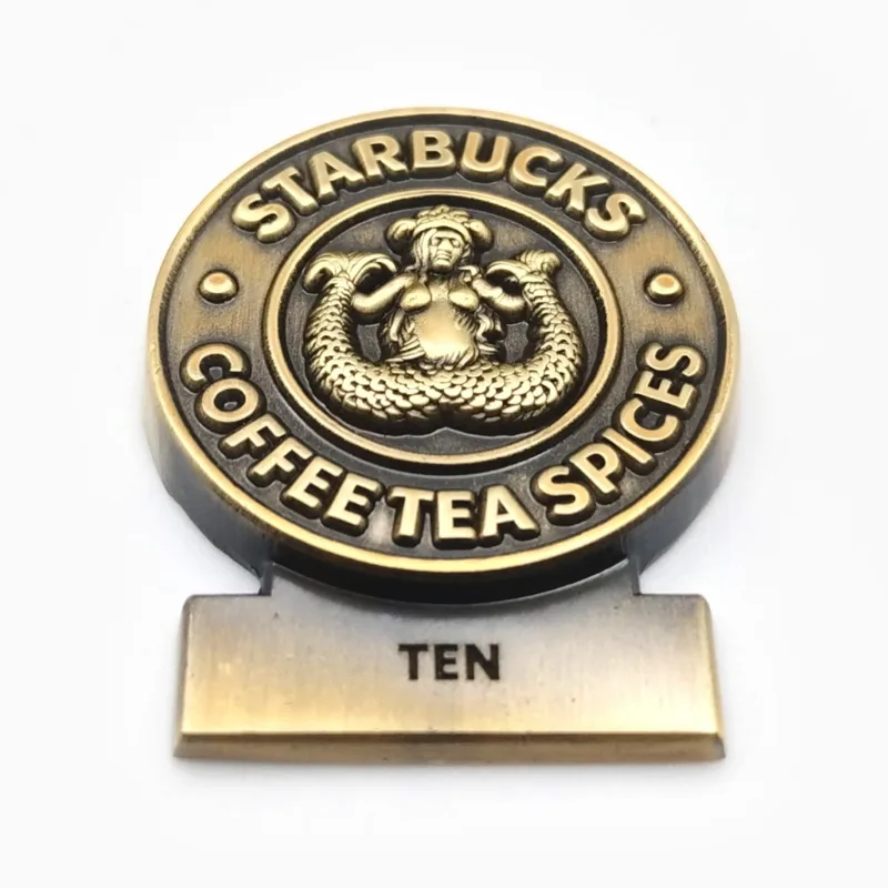 Pin emblema 3D en bronce envejecido con una placa que dice “Ten”, hecho para una cadena de cafeterías.