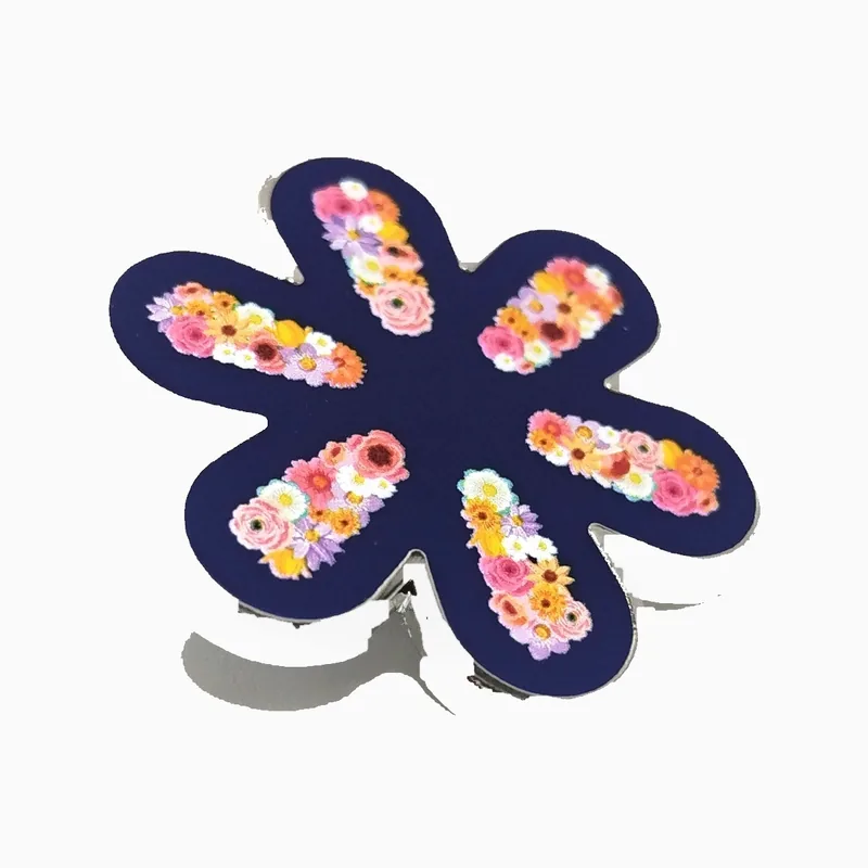 Pin impreso en forma de flor con racimos de flores sobre pétalos azul oscuro bajo una capa de epoxi transparente