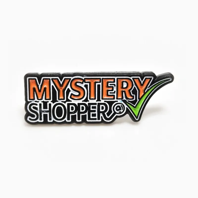 Pin troquelado de esmalte suave con baño de níquel negro, el texto «Mystery Shopper» en naranja y negro y una marca de verificación verde.
