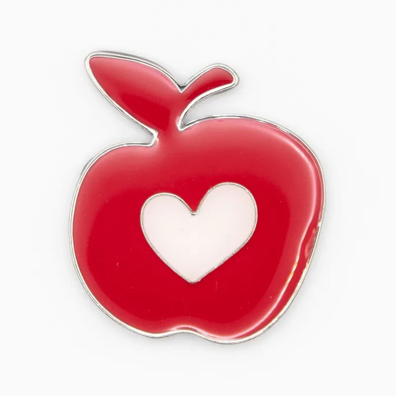 Pin de esmalte suave de una manzana roja con un corazón blanco calado y capa de epoxi transparente
