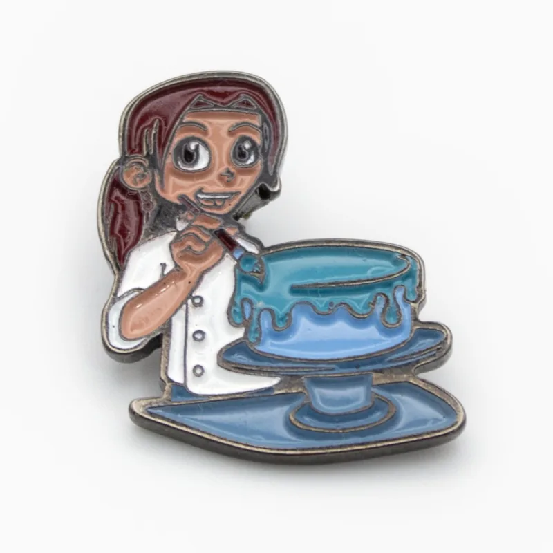 Pin de esmalte suave con baño negro de un personaje pastelero decorando un pastel azul