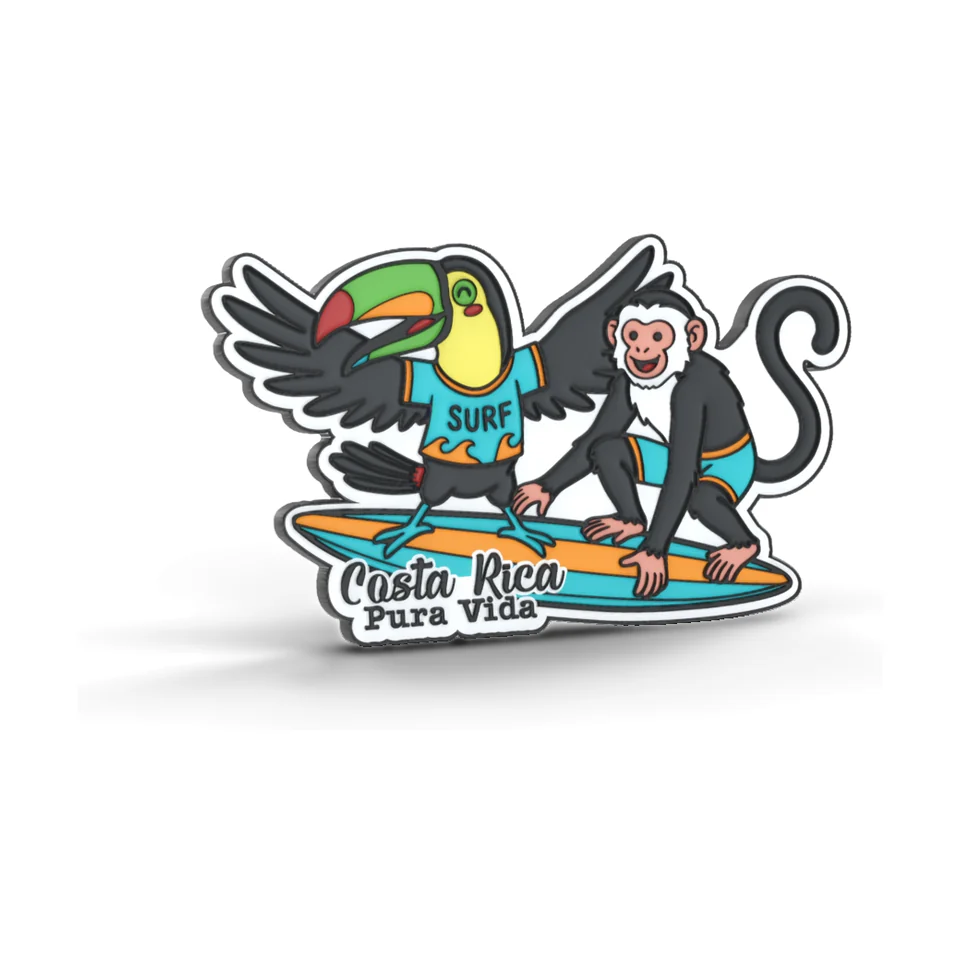 Imán de PVC suave de un tucán con camiseta SURF y un mono cariblanco sobre una tabla de surf, con el texto Costa Rica Pura Vida.